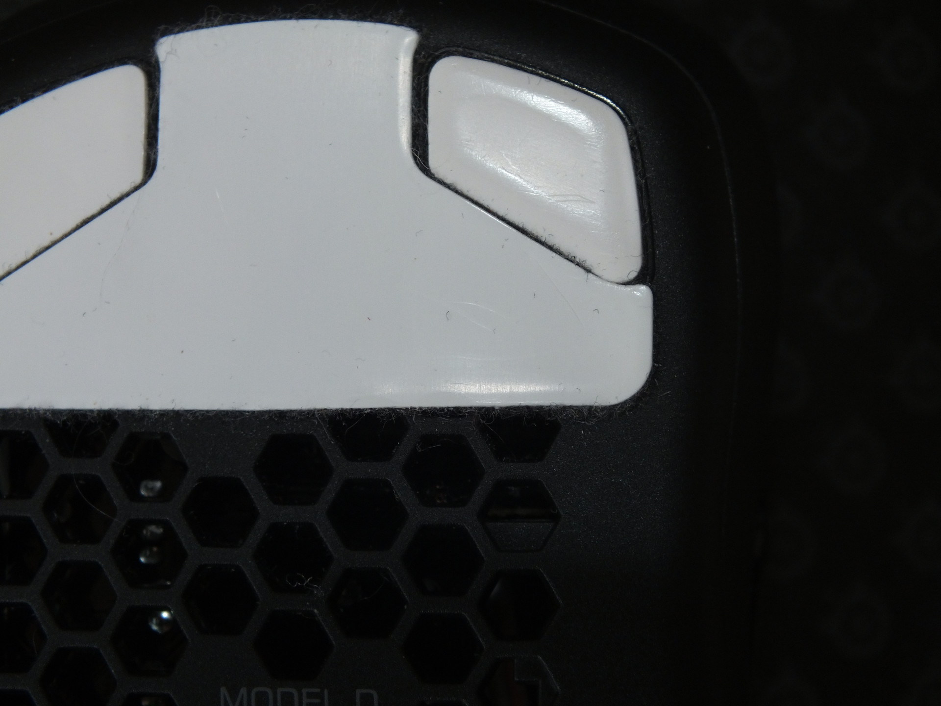 Nahaufnahme der oberen Mausgleiter der Model D. Anhand der Spiegelung ist die Form und erste Abnutzung erkennbar welche die Maus weicher gleiten lässt.