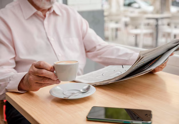 unrecognizable-man-reading-daily-newspaper-holding-up-cup-coffee-with-one-hand-cell-phone-him-...png